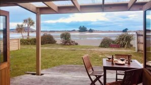 Un porche techado con mesa y sillas, con vista a la playa y el océano.