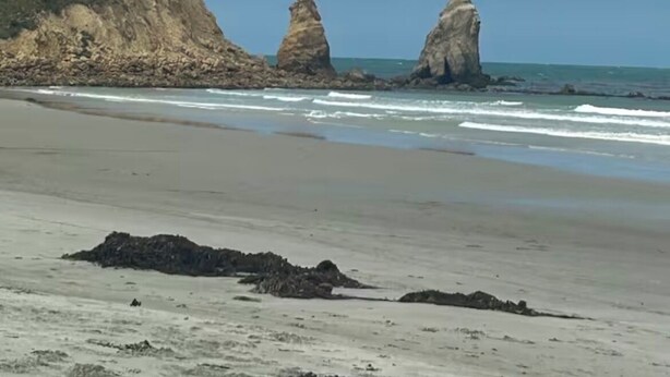 Una playa con formaciones rocosas y cielo despejado.