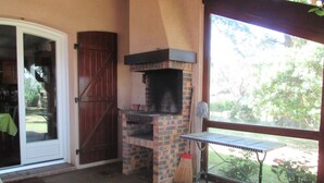 Area cucina esterna con forno in mattoni, un tavolo e una scopa.
