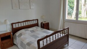 Una camera da letto con un letto di legno, due comodini, una finestra con tende e un'opera d'arte appesa al muro.