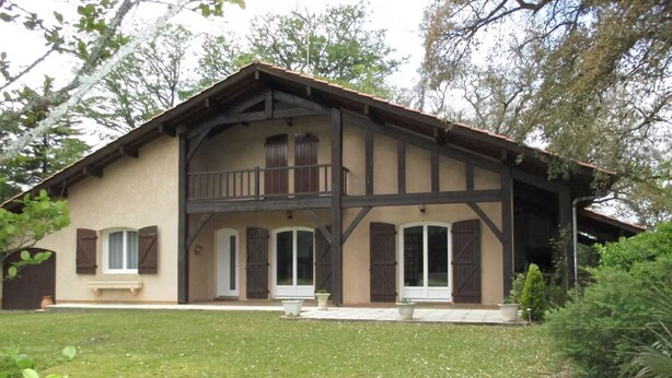 Una casa a due piani con un balcone, un portico anteriore e un prato curato.