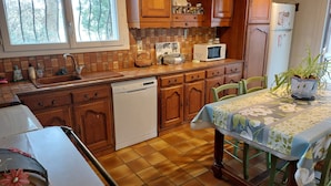 Una cucina con mobili in legno, lavastoviglie, forno a microonde e frigorifero.