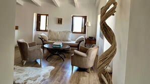 Un vaste salon doté d’un haut plafond, d’une grande sculpture tissée et d’un tapis en peau de vache.