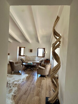 A spacious living room with a high ceiling, a large woven sculpture, and a cowhide rug. - Top floor, 3 double bedrooms, roof top, fabulous sea, mountain and village views (Santa-Reparata-di-Balagna)