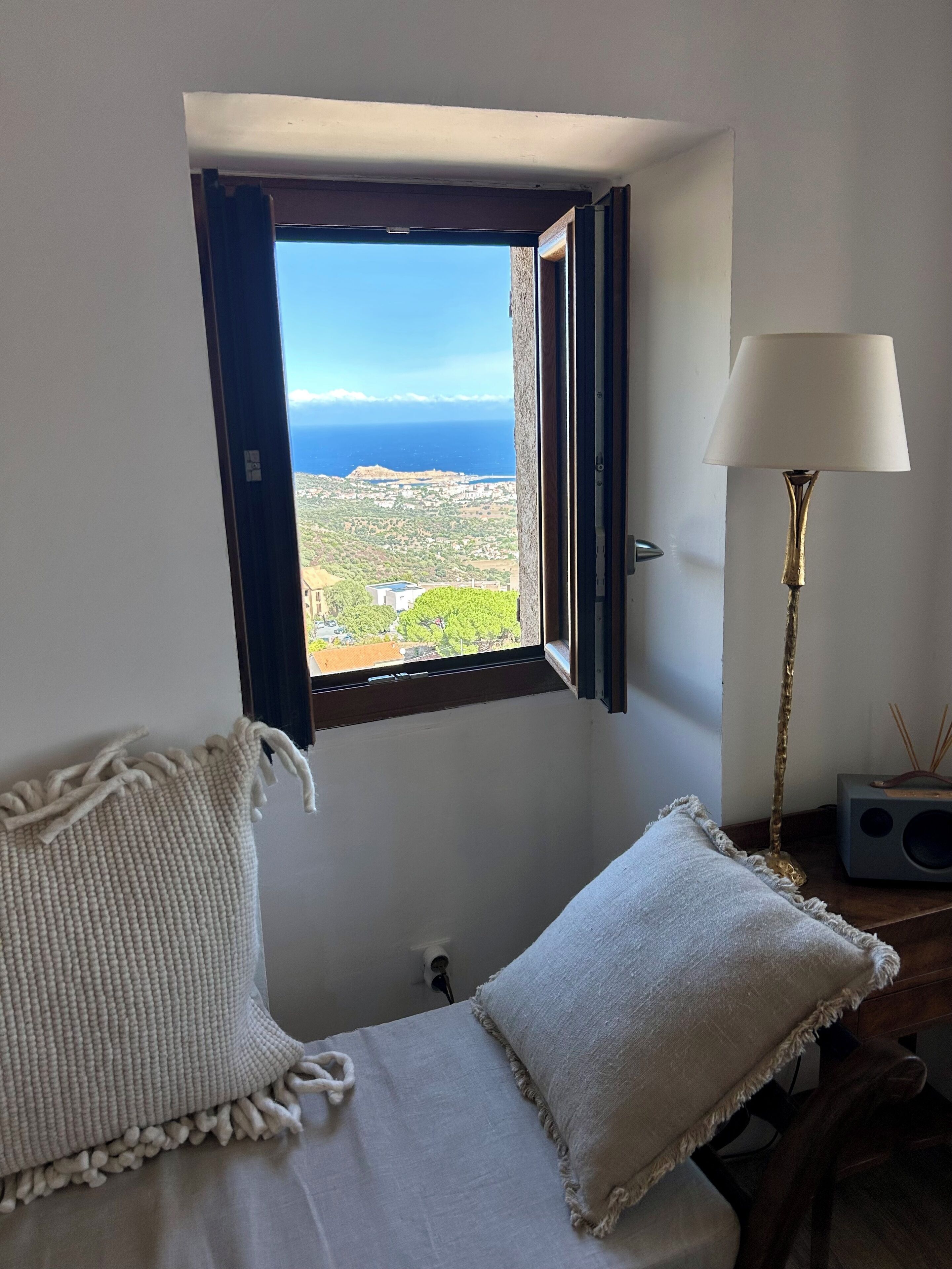 Une chambre avec vue sur la mer, une lampe et un haut-parleur sur une table de chevet.