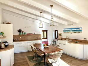 A modern kitchen with white cabinetry, wooden countertops, and a dining area with a wooden table and wicker chairs. - Top floor, 3 double bedrooms, roof top, fabulous sea, mountain and village views (Santa-Reparata-di-Balagna)