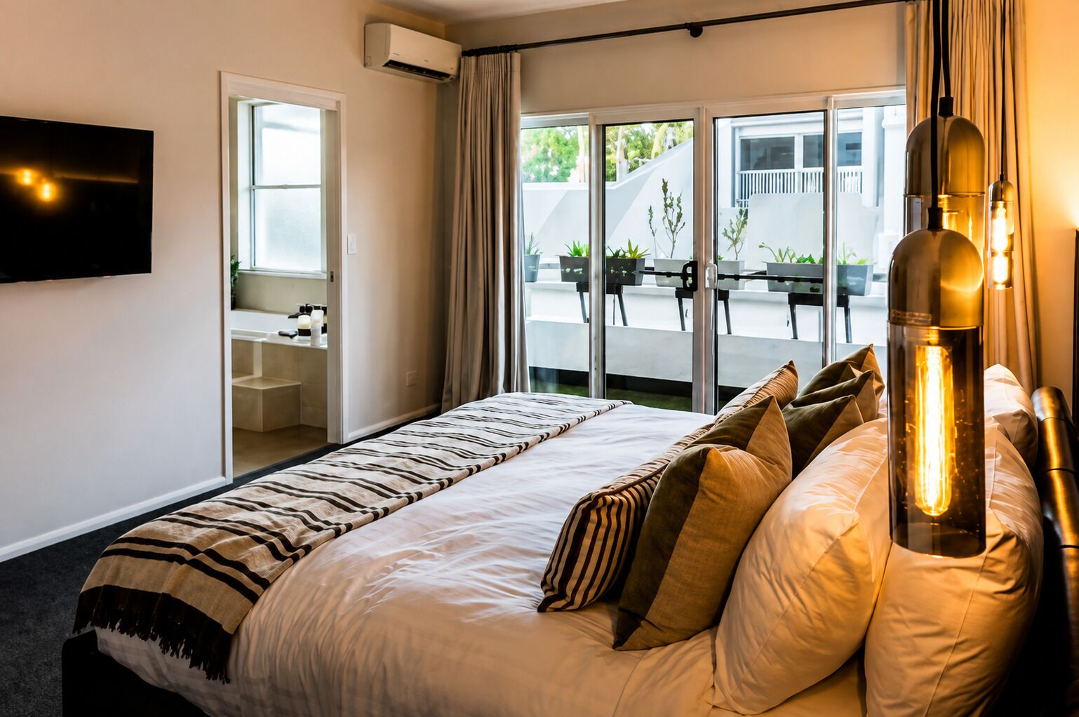 Une chambre d’hôtel avec un lit, un téléviseur fixé au mur, une fenêtre avec des rideaux et une vue sur l’extérieur.