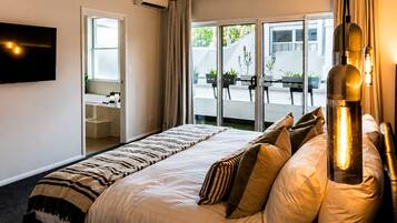 Une chambre d’hôtel avec un lit, un téléviseur fixé au mur, une fenêtre avec des rideaux et une vue sur l’extérieur.
