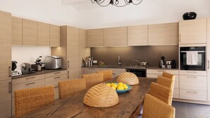 Eine moderne Küche mit Holzausstattung, einem Esstisch mit Korbstühlen und einer Kronleuchter.