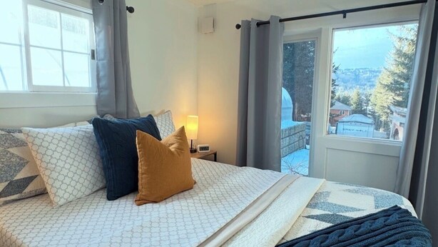 Un dormitorio con una cama grande, una ventana con cortinas y vistas a un paisaje nevado.