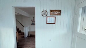 Un pasillo con una puerta de madera que da a una escalera. Un letrero en la pared dice "BEACH".