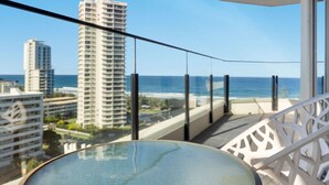 A balcony with a glass table and white railing, overlooking a beach and high-rise buildings. - Beach Haven Getaway Broadbeach - WiFi, Parking (Broadbeach)