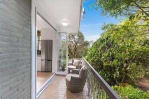 A balcony with wicker furniture, a stainless steel refrigerator, and a view of greenery. - Salty`s at Burleigh - Central, Spacious, WiFi (Burleigh Heads)