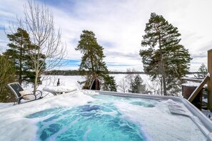Lämminvesiallas, jonka ympärillä on lumipeitteisiä puita, ja josta avautuu näkymä järvelle.