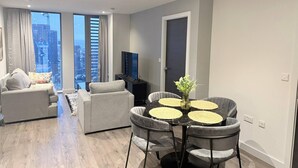 Ein modernes Wohnzimmer mit Essbereich, großen Fenstern und Blick auf die Stadt.
