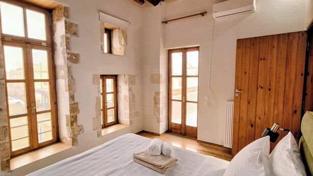 Ein Zimmer mit Holzboden, einem Bett mit weißen Bettwäsche, einem Fenster und einer Heizung.