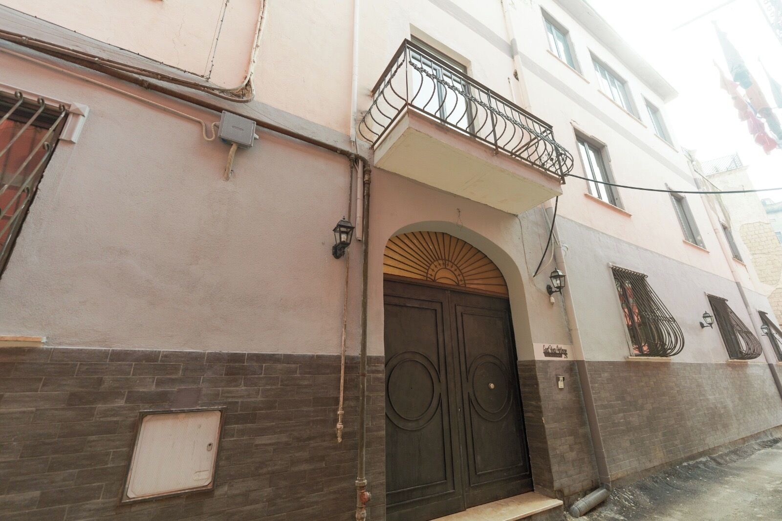 A building with a dark brown door, a small balcony with a metal railing, and a sign above the door that reads "Casa de Campo".