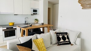 Een moderne keuken met witte kasten, een magnetron en een gele pan op het fornuis.