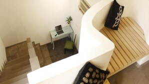 A staircase with a desk and chair, a plant, and a cushioned bench with a pillow. - Ayatti By Caparo (Greater Noida)