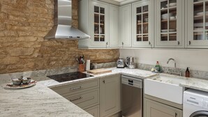 A kitchen with a stone wall, a stainless steel range hood, a dishwasher, and a sink with a Siemens brand dishwashing machine. -  Beautiful one bedroom barn in the rural hamlet of North Wraxall (North Wraxall)
