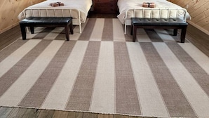 Une chambre confortable dans un chalet, avec deux lits, un plafond en bois et un tapis à carreaux.