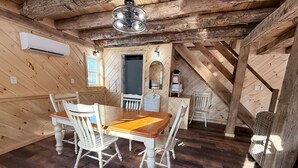 Une salle à manger rustique, avec une table et des chaises en bois, un ventilateur de plafond et une fenêtre offrant une belle vue.