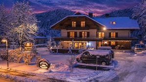 A snow-covered lodge with a sign indicating it is a post inn. - Ferienhof Alte Post (Gitschtal)