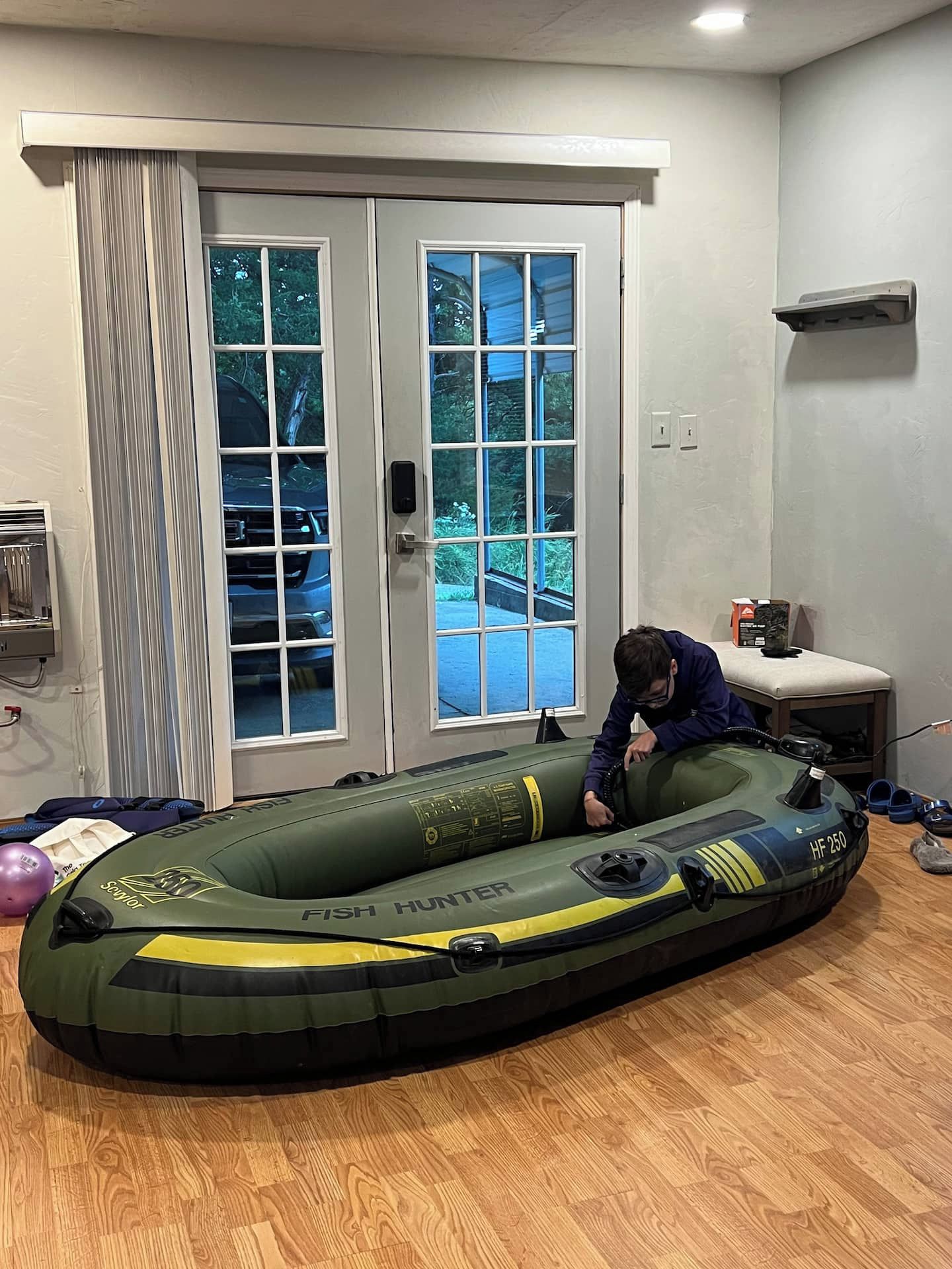 A room with a large inflatable raft, a door with glass panels, and a small table with a plant.