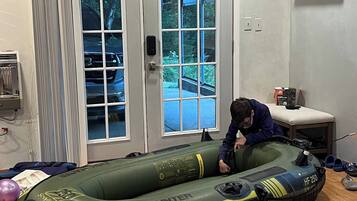 A room with a large inflatable raft, a door with glass panels, and a small table with a plant.