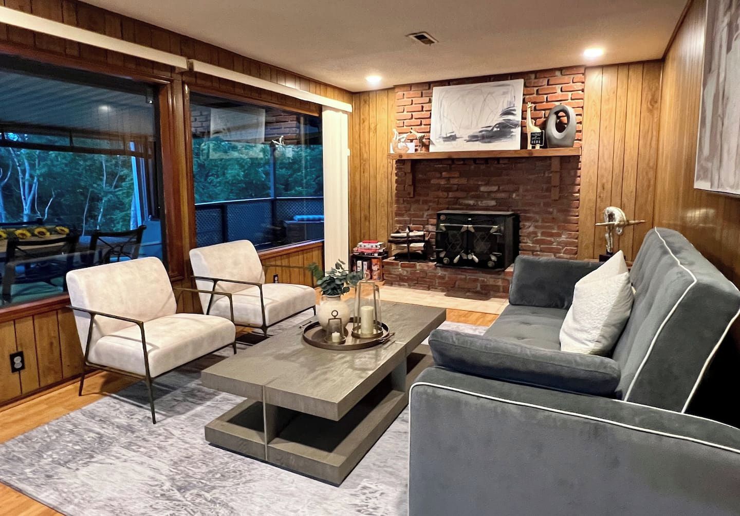 Un salon moderne avec une cheminée, deux fauteuils, un canapé et une table basse.
