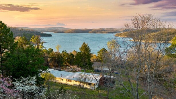 A lakeside property with a house, trees, and a view of the water.