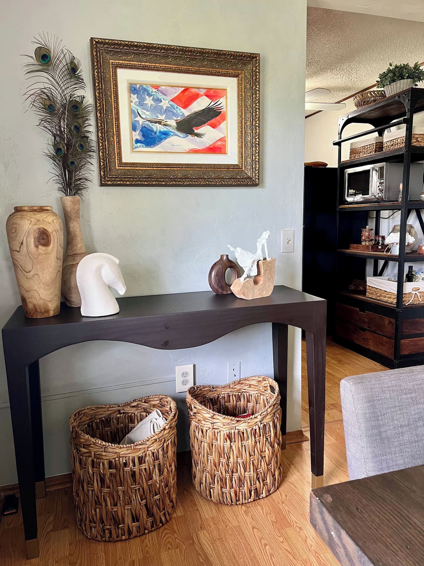 A dark wooden table with decorative items, two woven baskets, and a framed artwork above.