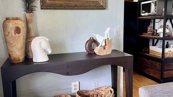 A dark wooden table with decorative items, two woven baskets, and a framed artwork above.