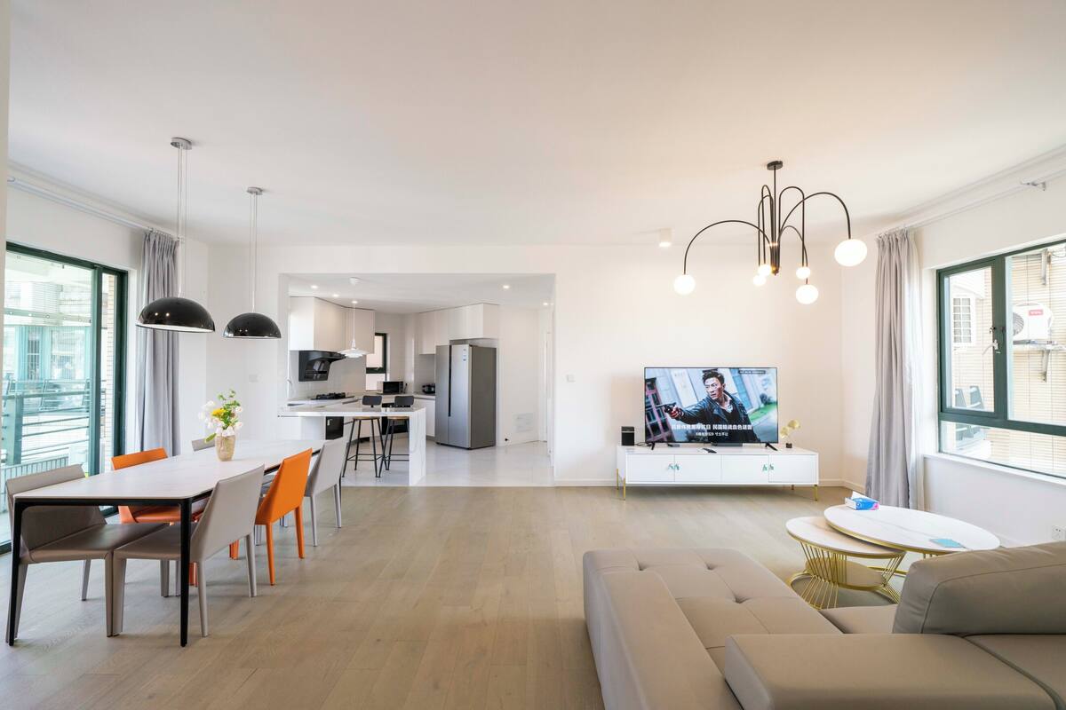 Una sala moderna con sofá, mesa de comedor y televisión.
