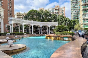 A swimming pool with a white gazebo, surrounded by greenery and tall residential buildings. - Tyms High Serviced Residence Shanghai Xujiahui Tower (Shanghai)