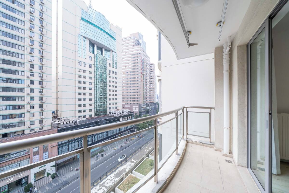 Un balcón con vista a un paisaje urbano, con edificios altos y una carretera.
