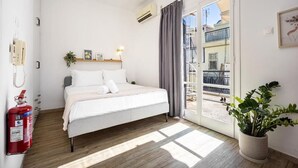A bedroom with a bed, a fire extinguisher, a potted plant, and a view of the outside balcony. - Athens Nala (Athens)