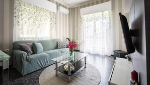 A living room with a green sofa, a glass coffee table, a TV on the wall, and a chandelier. - Athens Nala (Athens)