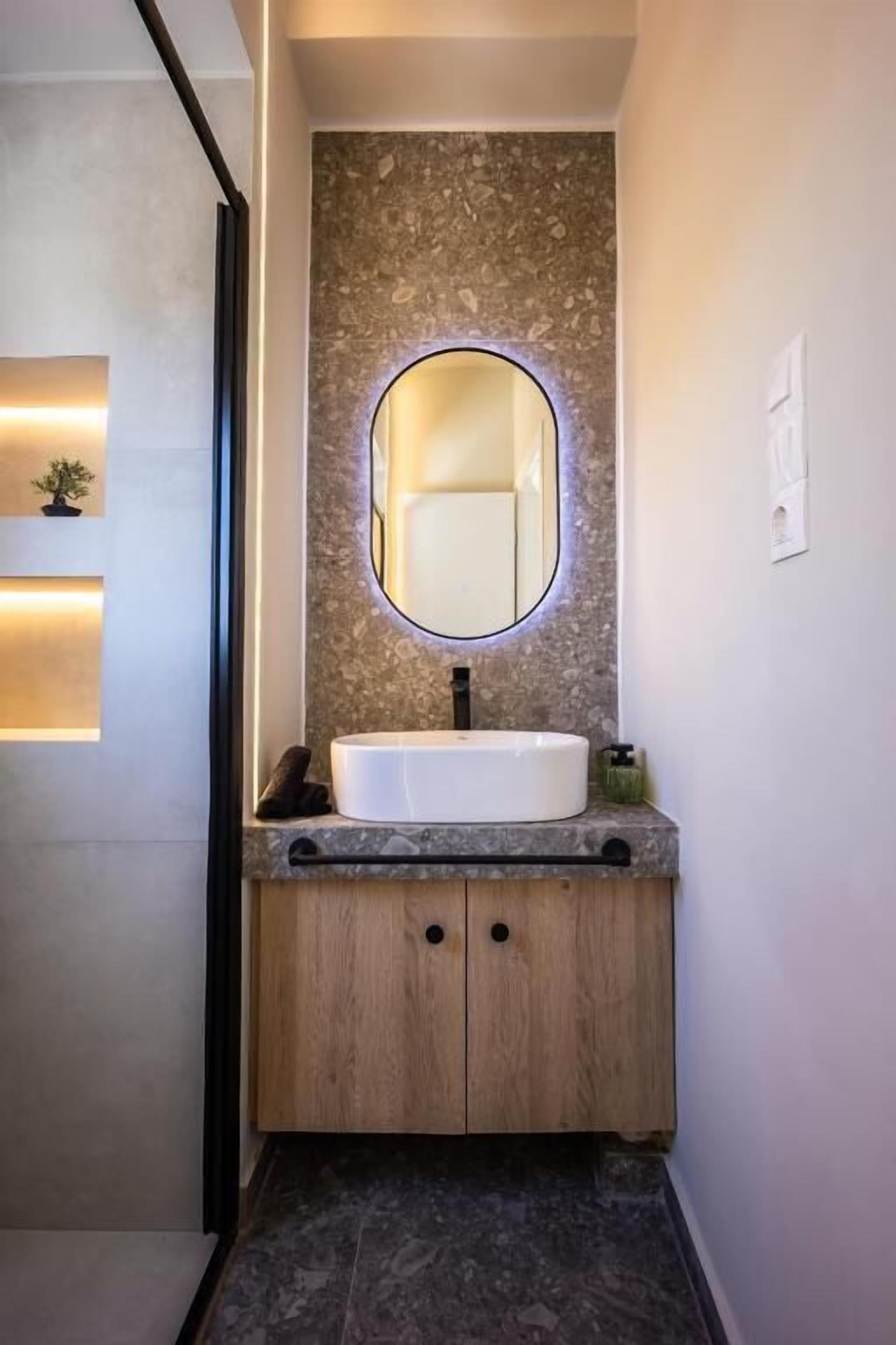 A modern bathroom with a freestanding sink, a round mirror, and a small plant on the countertop.