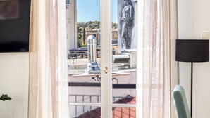 A room with a door leading to a balcony, a statue, a television, and a chair. - Athens Nala (Athens)