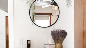 A wooden dresser with a mirror, a vase with dried flowers, a box, and a remote control.