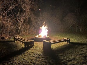 A campfire with a metal grill in a grassy area surrounded by trees. - Hot Tub | Outdoor Living | Game Room | Coffee Bar (South Bend)