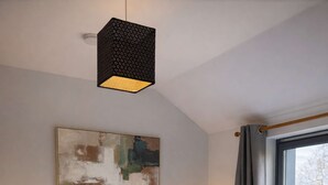 Ein Schlafzimmer mit einem Bett, Nachttischlampen, einem Fenster mit Vorhängen und einem Bild an der Wand.