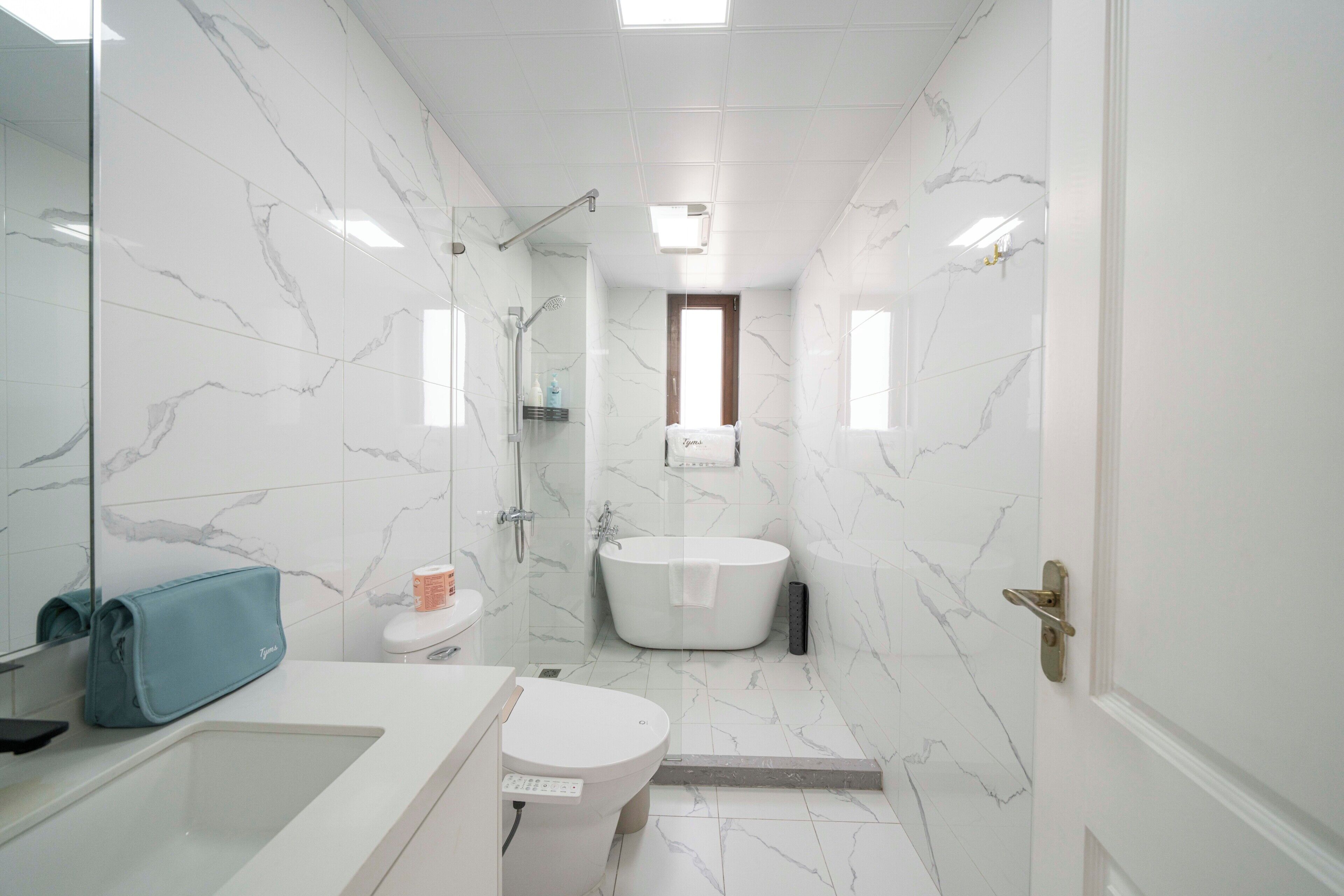 A modern bathroom with a bathtub, toilet, and glass shower enclosure.