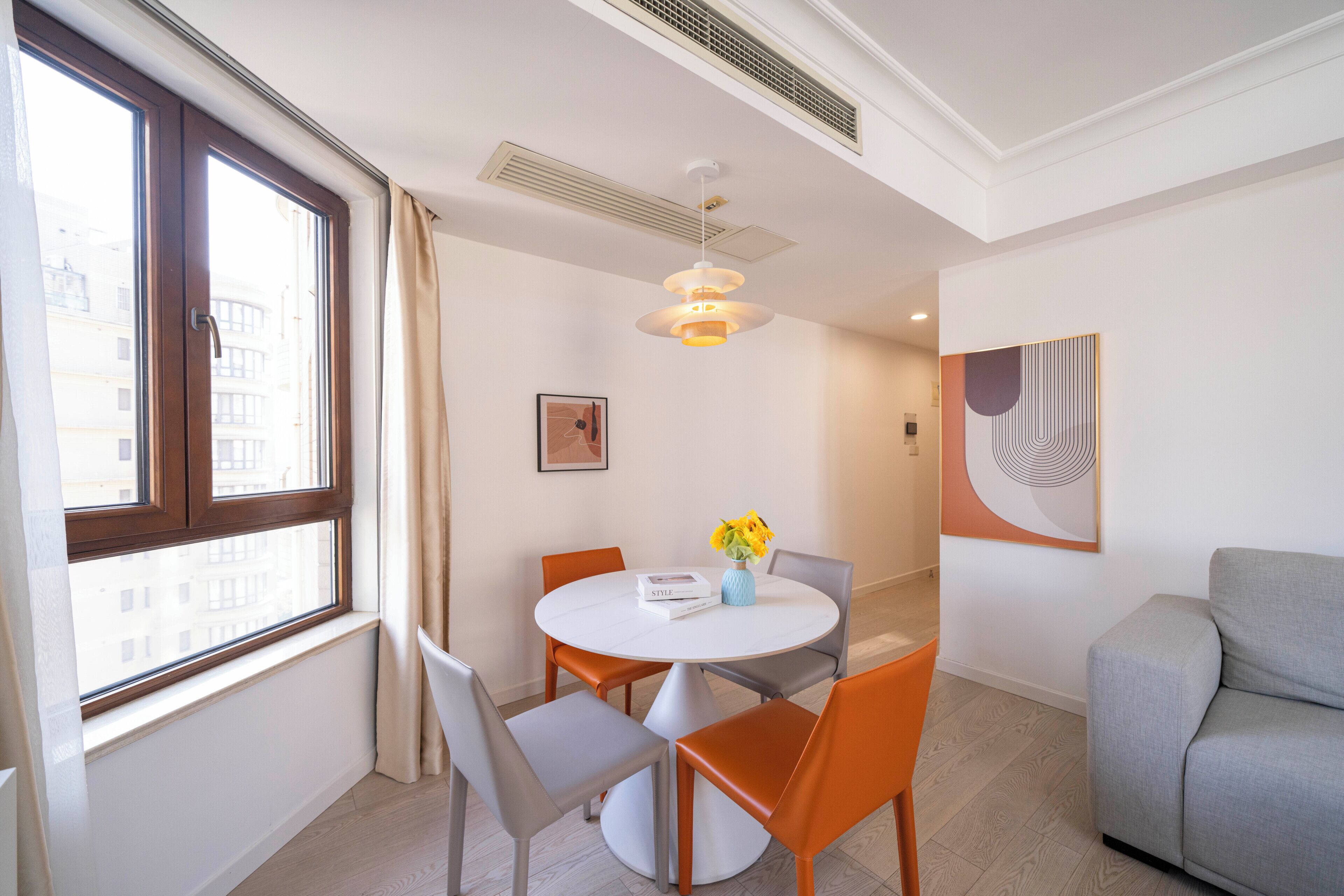 Un espace repas moderne avec une table ronde, des chaises et un vase de fleurs.