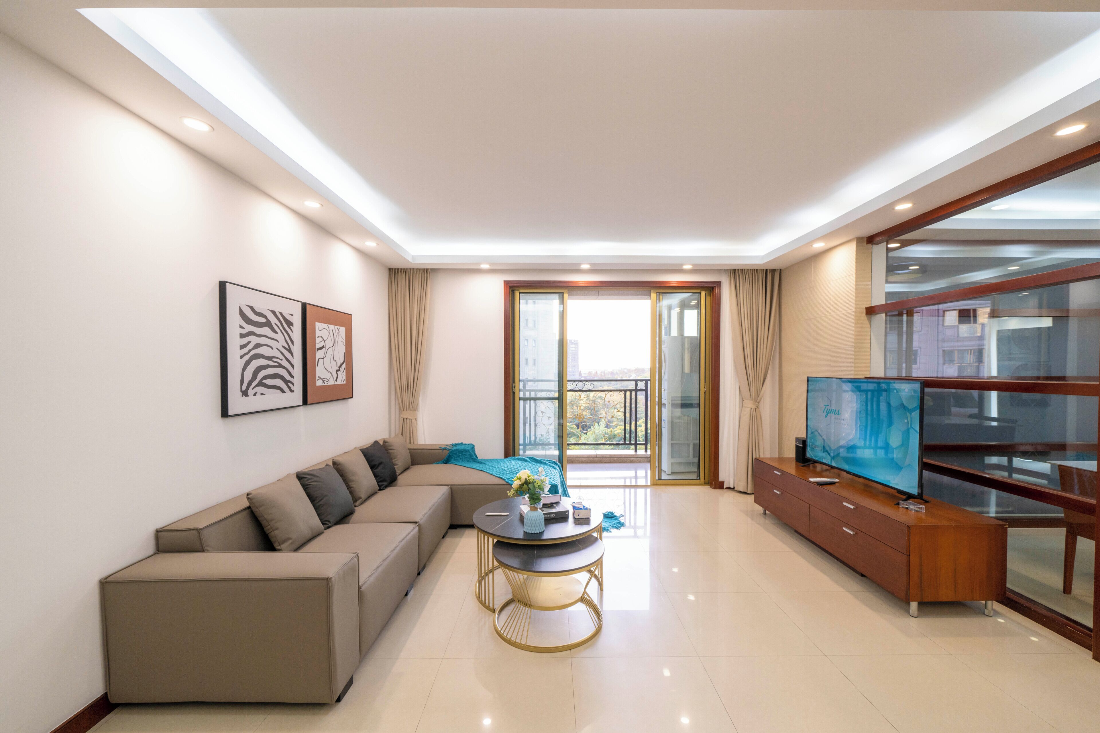 Una sala de estar moderna con un sofá, una mesa de centro, un televisor y un balcón con puerta de vidrio.
