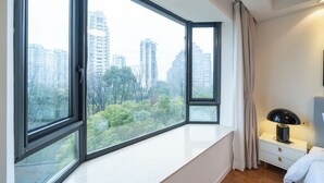 A bedroom with a large window, a bedside table, a lamp, and a bed. - Tyms High Serviced Residence Gubei International (Shanghai)