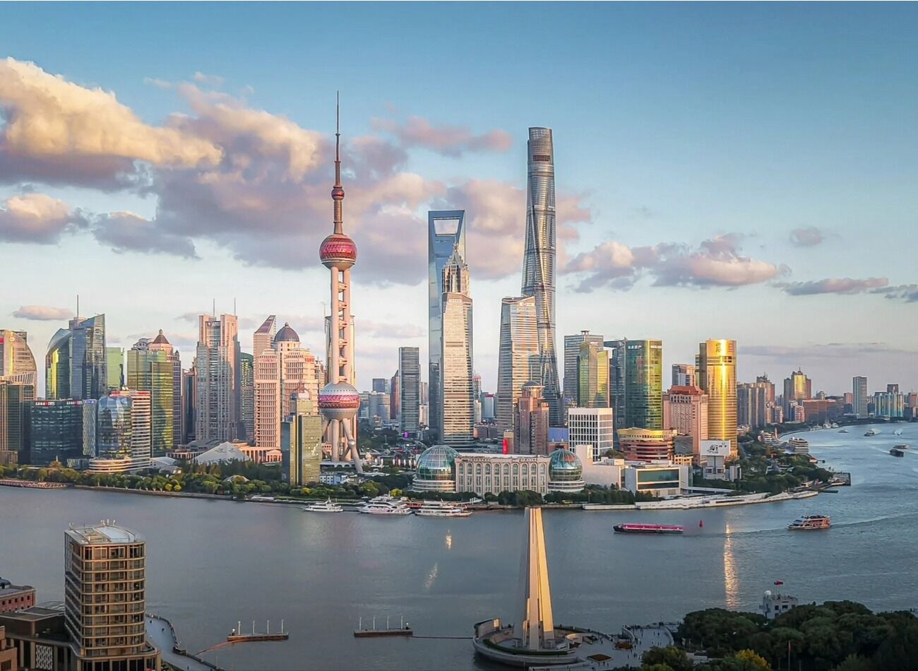 A city skyline with modern skyscrapers, a prominent tower, and a river with boats.