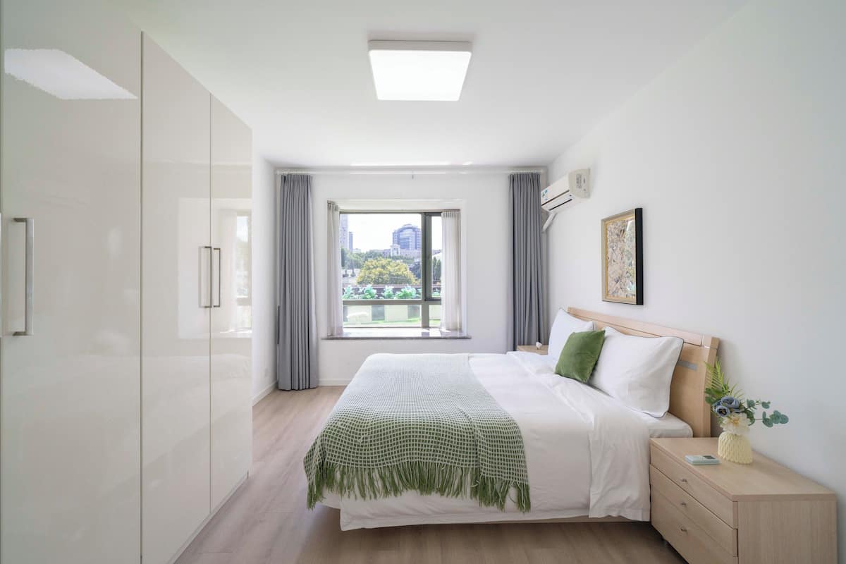 Une chambre à coucher avec un lit, une table de chevet et une fenêtre avec des rideaux.