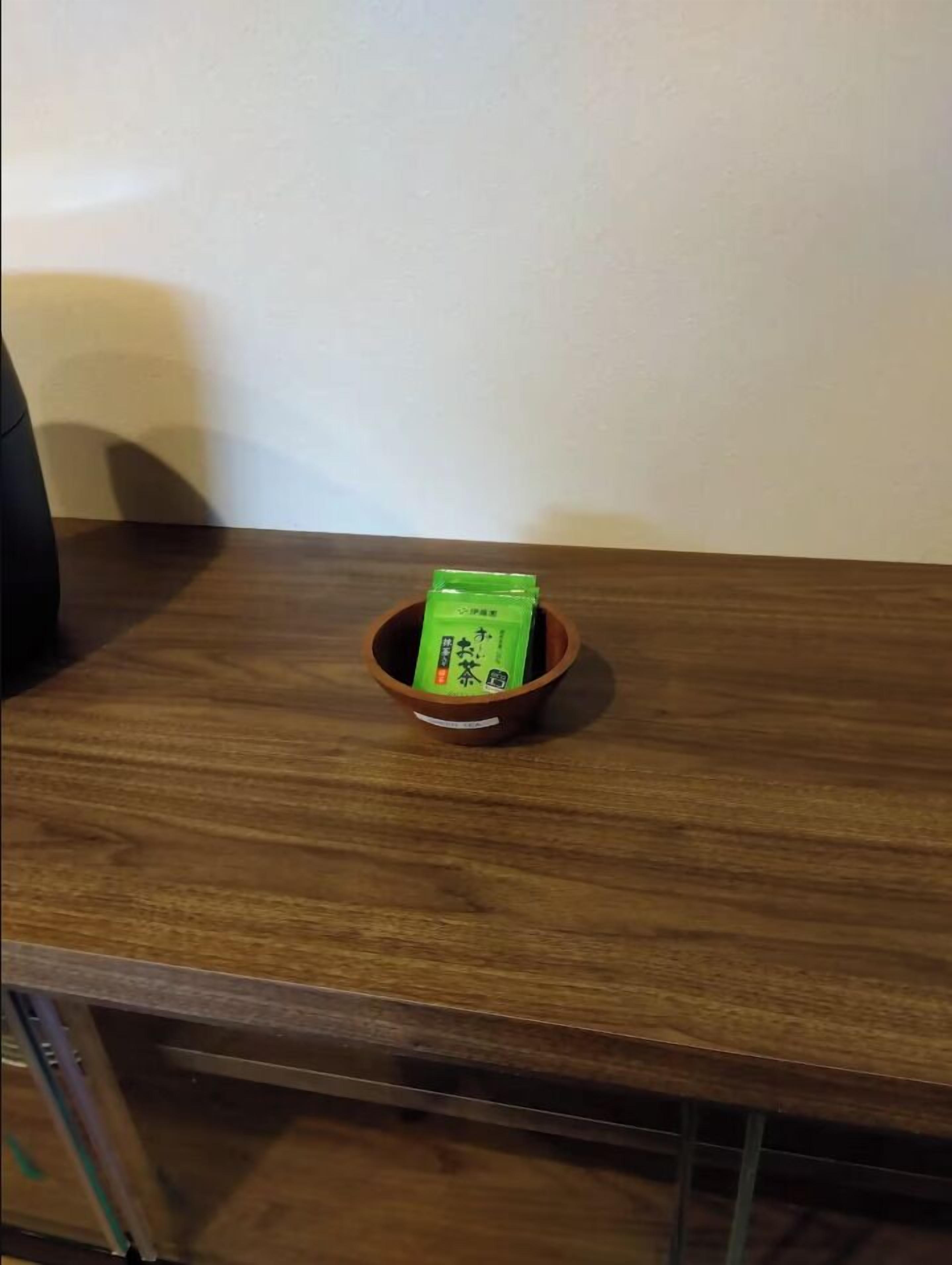 A wooden table with a small brown bowl containing a green object.